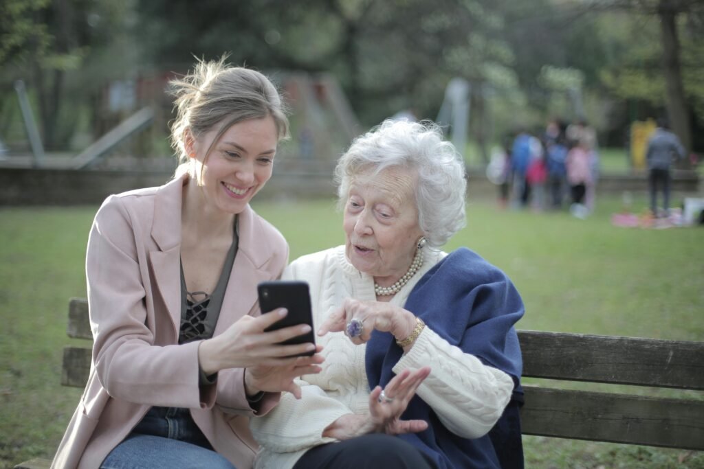 pexels photo 3791664 3791664 Delighted female relatives sitting together on wooden bench in park and browsing mobile phone while learning using